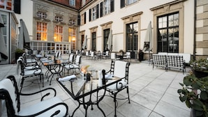 An outdoor cafe with tables and chairs, a bench, and a potted plant. - Schlosshotel Berlin  (Berlin)