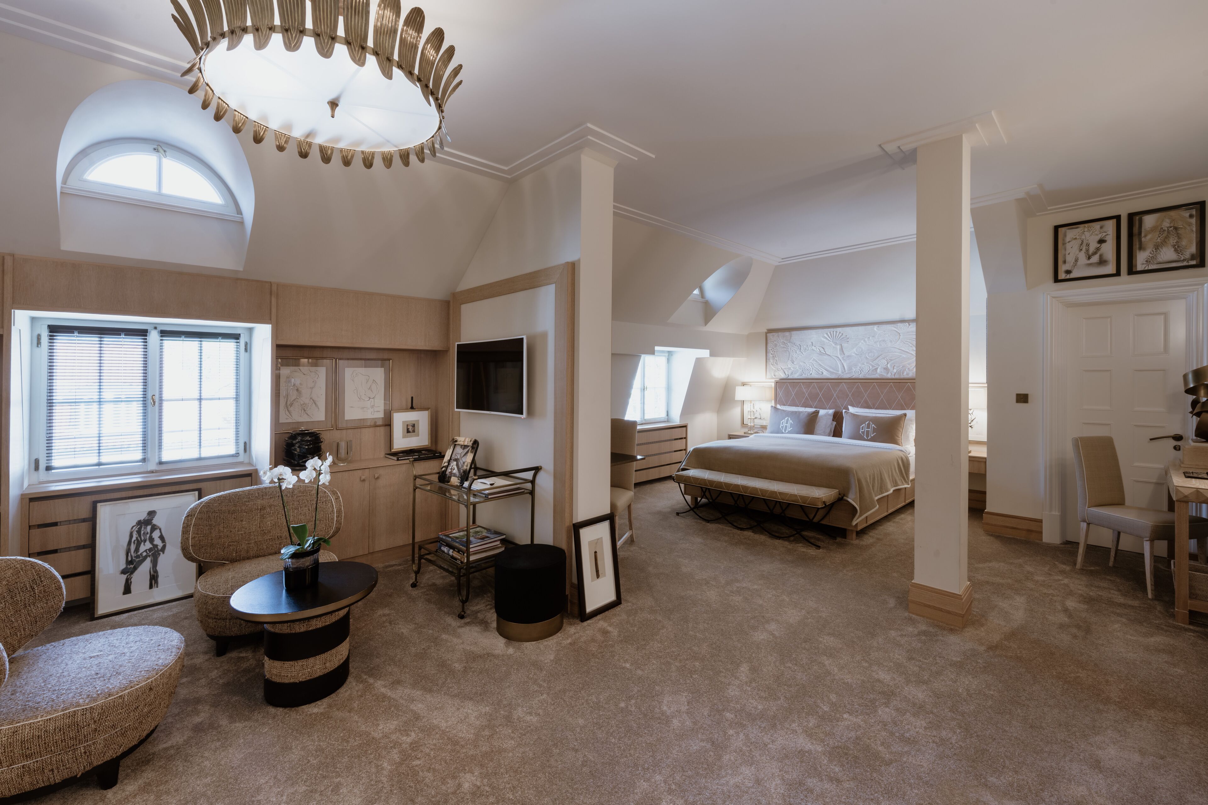 Een ruime slaapkamer met een groot bed, een zithoek met een tafel en stoelen, en een televisie.