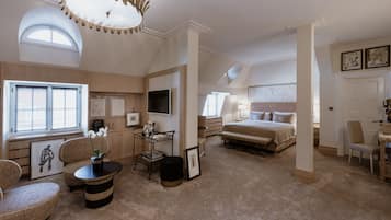 Een ruime slaapkamer met een groot bed, een zithoek met een tafel en stoelen, en een televisie.
