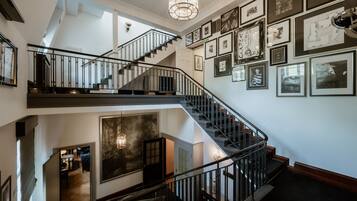 A multi-level interior with a staircase, framed pictures on the walls, and a chandelier.