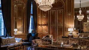A luxurious room with ornate wood paneling, a grand chandelier, and plush seating. - Schlosshotel Berlin  (Berlin)
