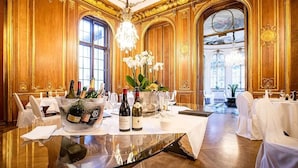 A luxurious dining room with a round glass table, elegant white chairs, and a chandelier. - Schlosshotel Berlin  (Berlin)