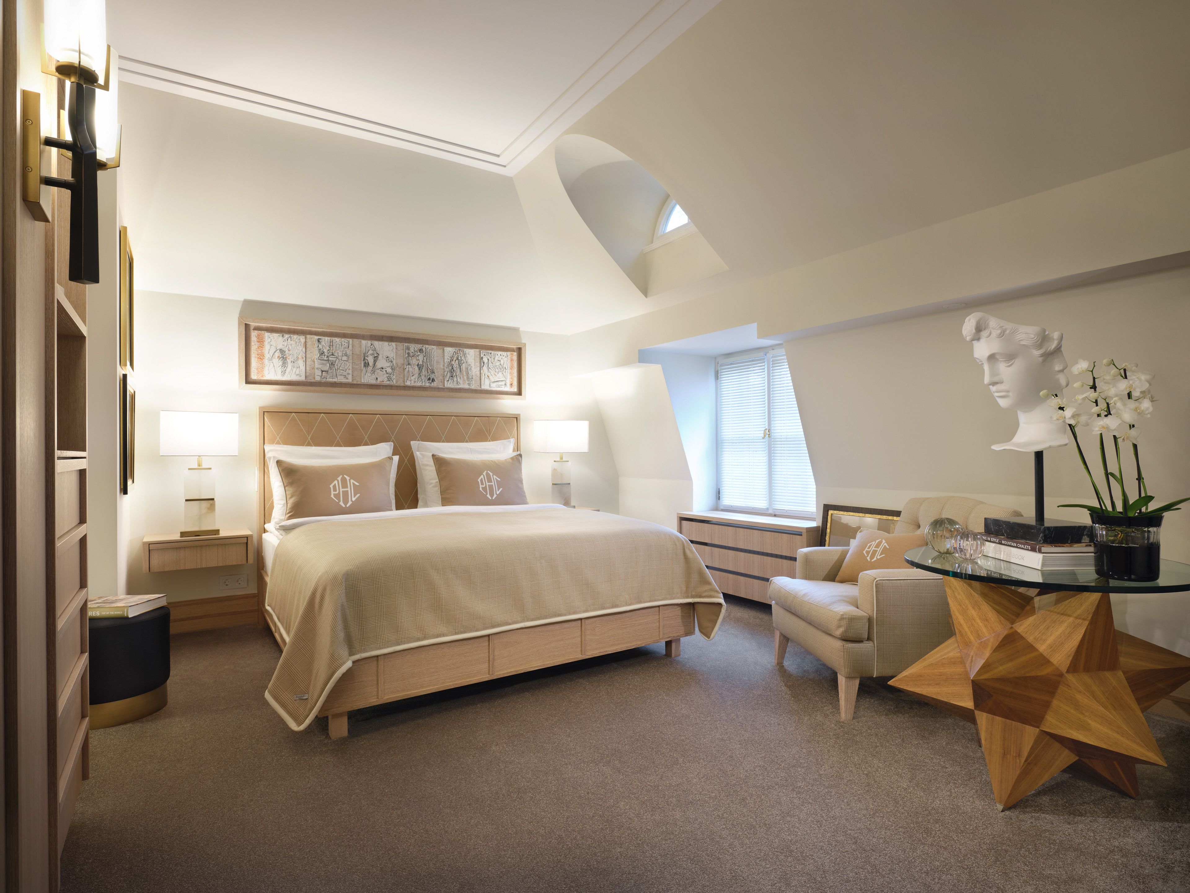 Ein modernes Schlafzimmer mit einem großen Bett, Nachttischen, einem Schreibtisch und einem Sessel.