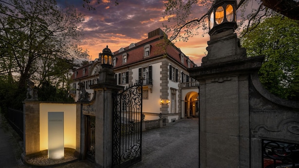 A historic building with a stone facade, a gated entrance, and a well-lit interior. - Schlosshotel Berlin  (Berlin)
