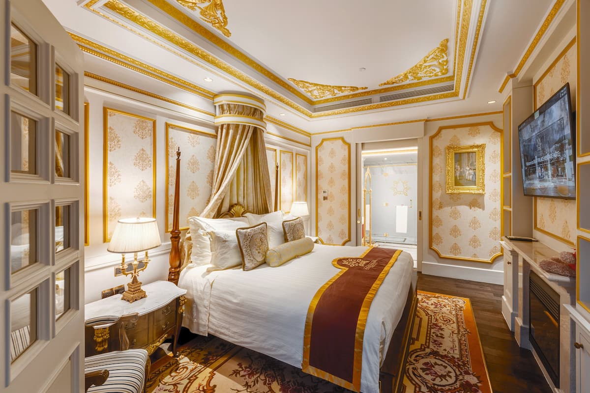 Een luxueuze slaapkamer met een groot bed, een versierd plafond en klassieke inrichting.