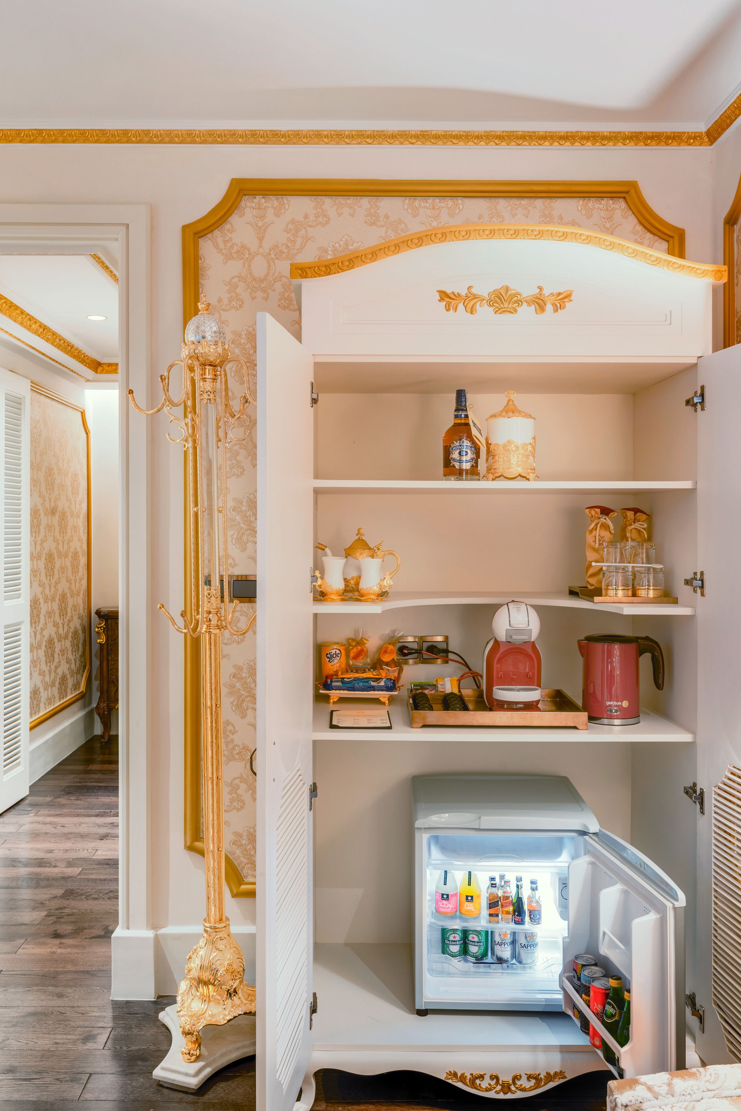 A luxurious room with a white minibar, gold accents, and a decorative mirror.