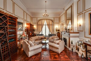 A luxurious living room with a large chandelier, a wine cellar, and a fireplace.