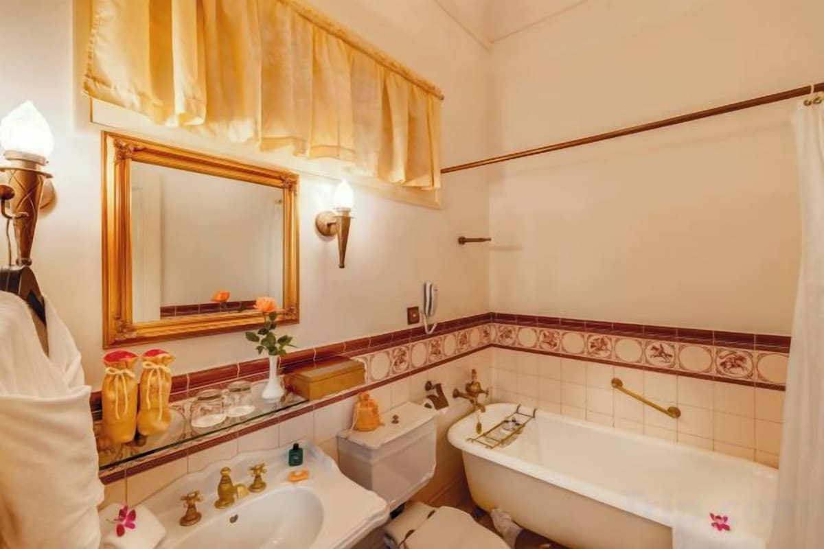 Un baño con bañera, lavamanos, espejo y toallero.