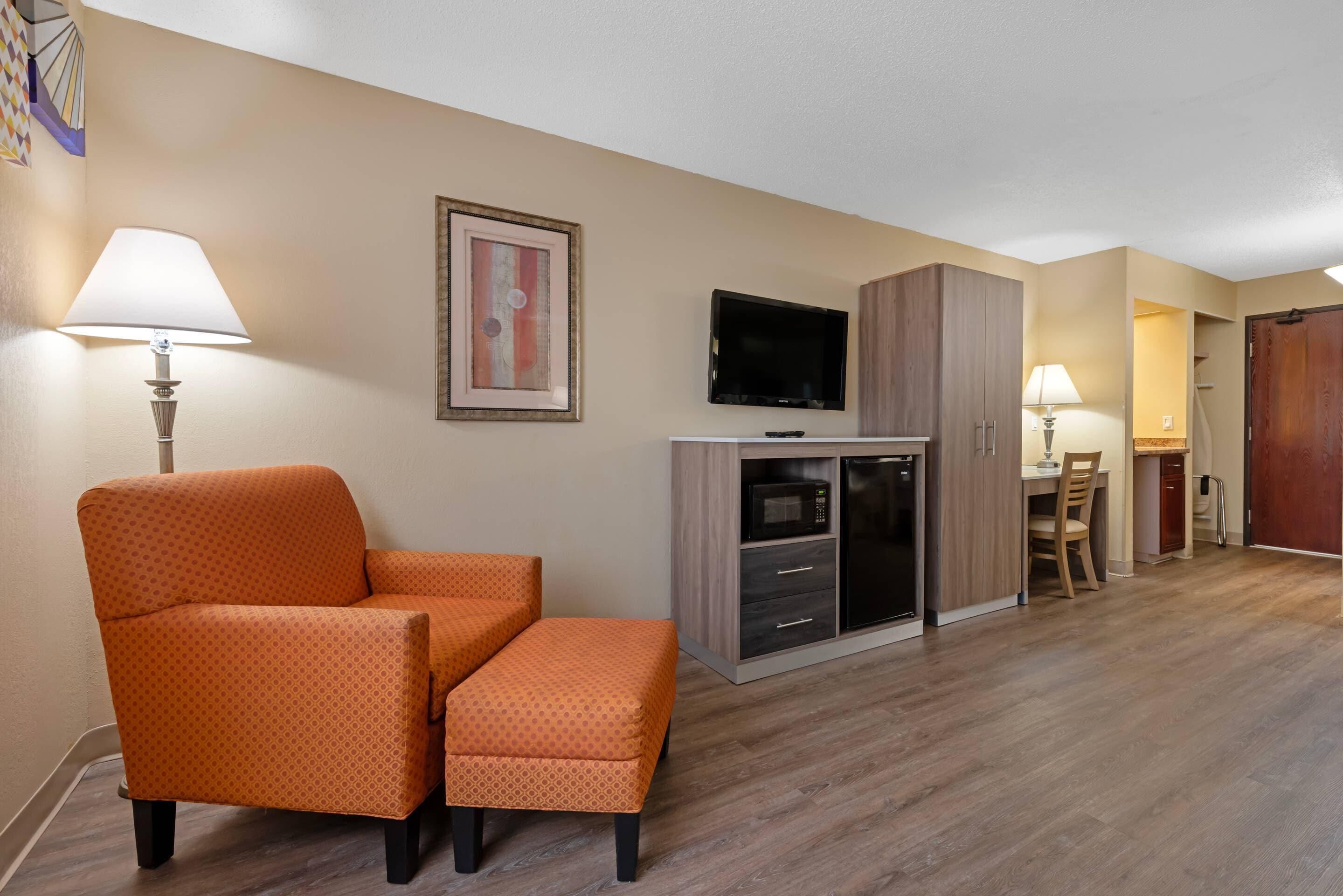 A hotel room with a sofa, a TV, a microwave, and a dining area.