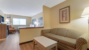 Una sala de estar con un sofá estampado, una mesita, un televisor y una ventana.