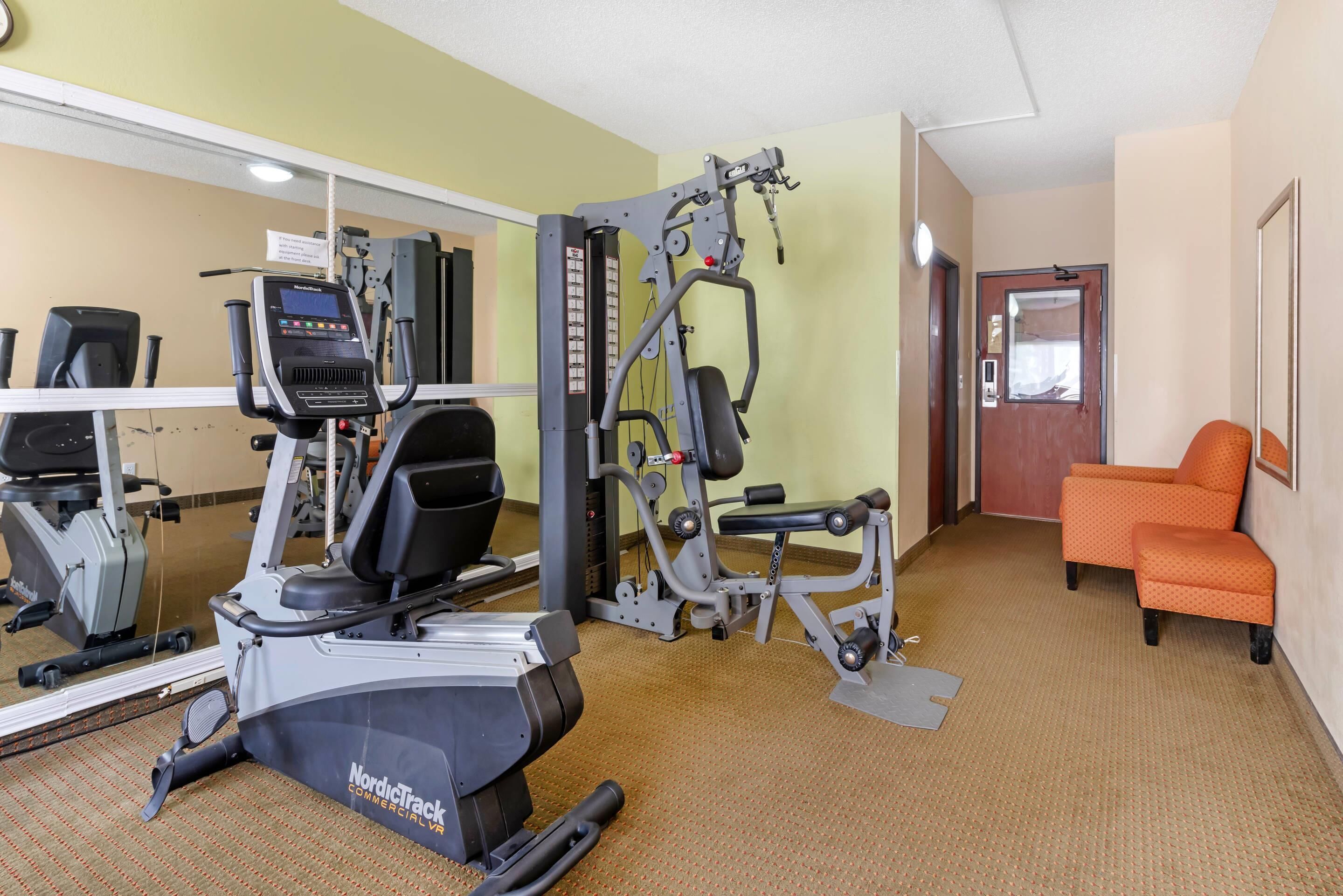 A gym with cardio machines, weight training equipment, and a mirror.