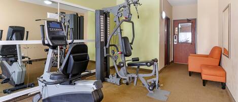 A gym with cardio machines, weight training equipment, and a mirror.