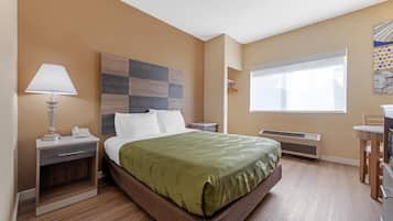 A hotel room with a bed, bedside table, lamp, and a window with a view.