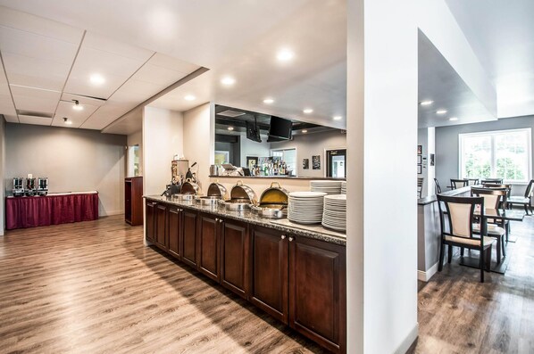 A modern kitchen with a long counter, built-in appliances, and a dining area with chairs and tables. - Carradoc Hall Hotel & Conference Center by The Red Collection (Leesburg)