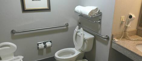 Un baño estándar con inodoro, bidé, secamanos y un cuadro en la pared.
