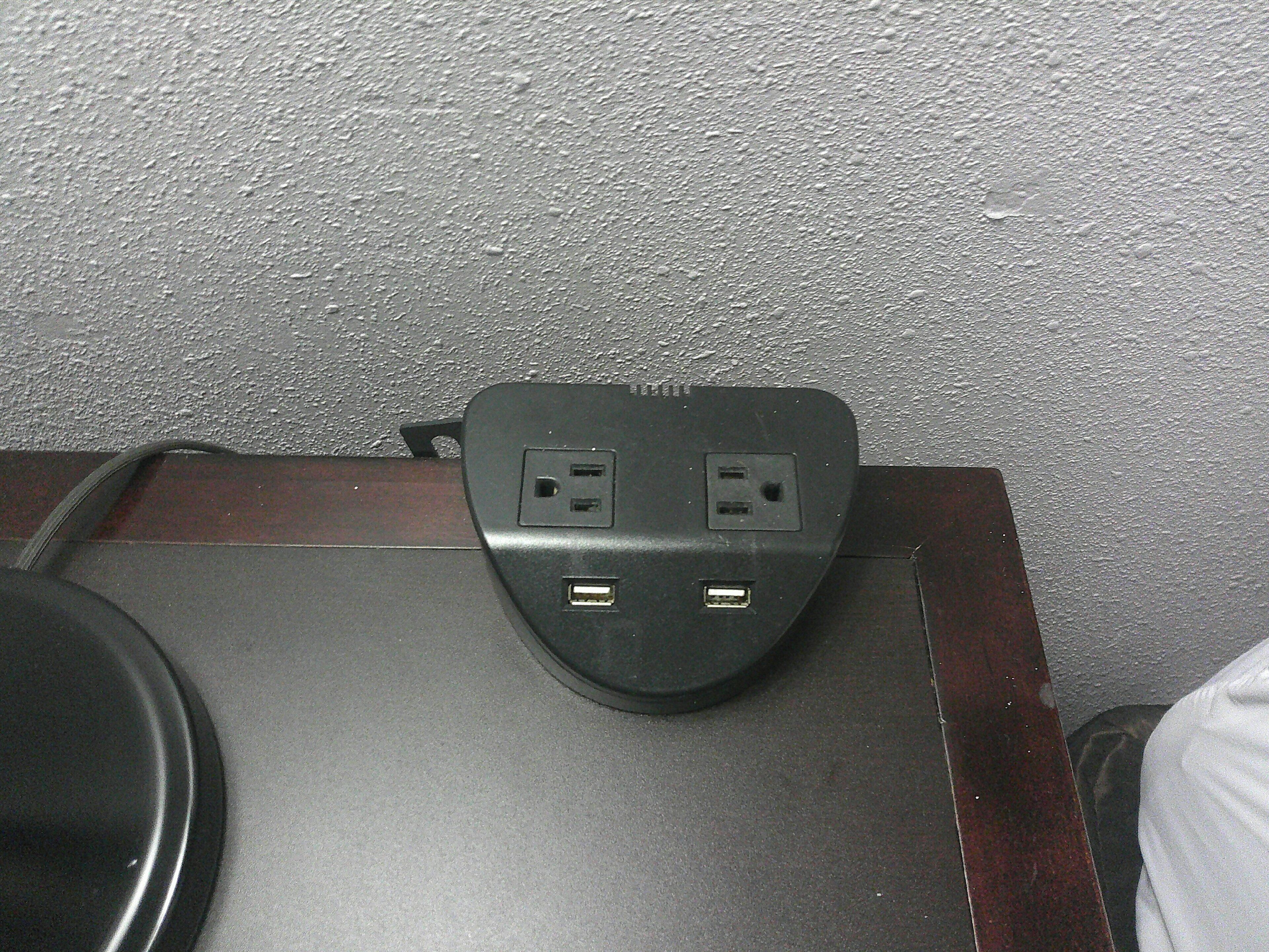 A black power strip with two USB ports and two standard electrical outlets on a dark surface.