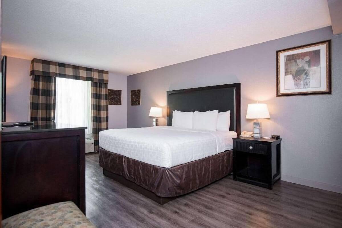 A hotel room with a large bed, two bedside tables with lamps, a desk, and a chair.