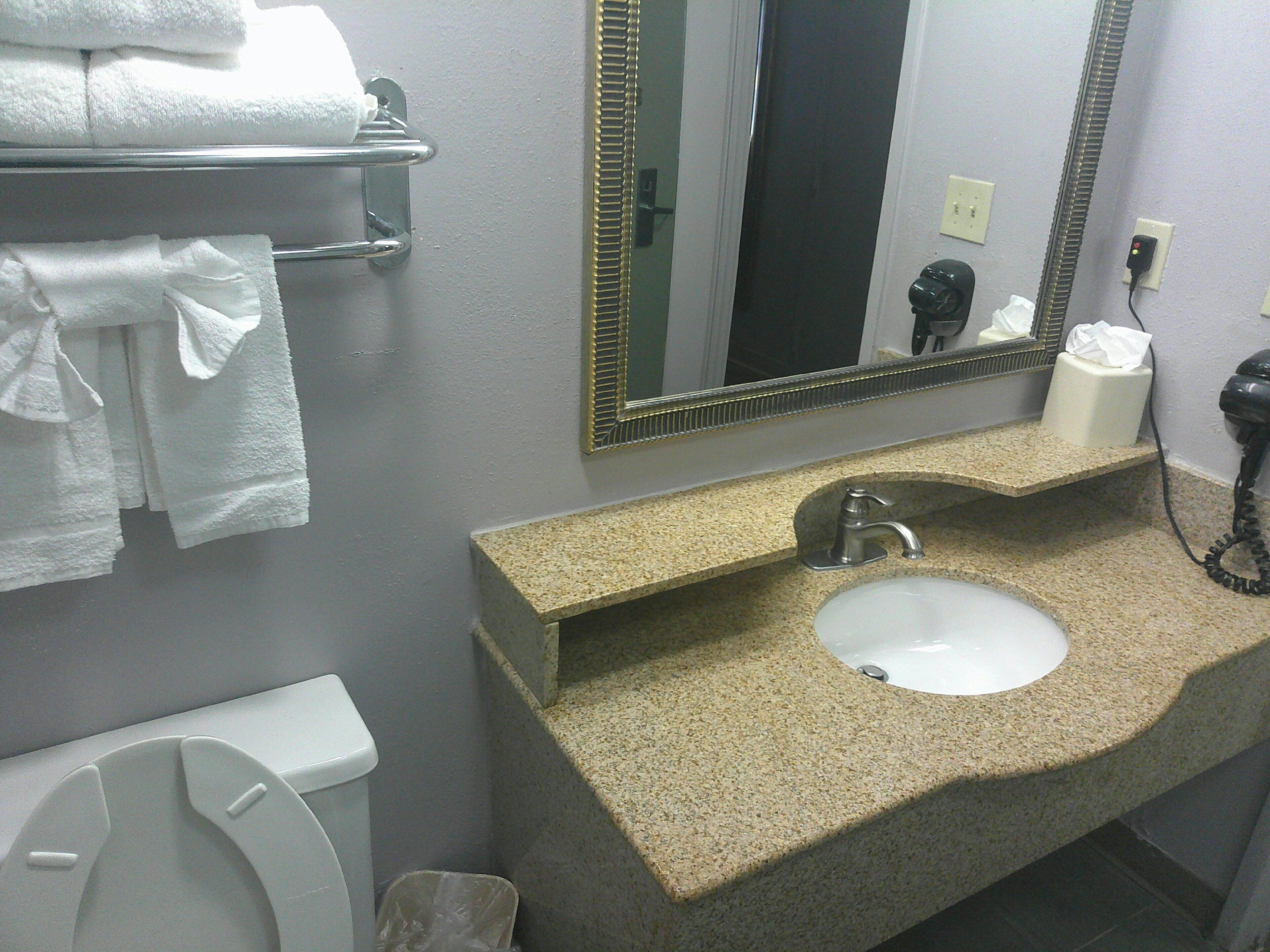 A bathroom with a sink, mirror, towel rack, toilet, and a hair dryer.