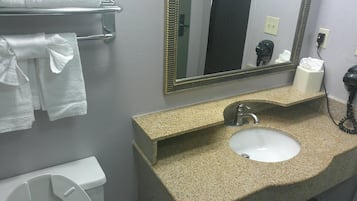 A bathroom with a sink, mirror, towel rack, toilet, and a hair dryer.
