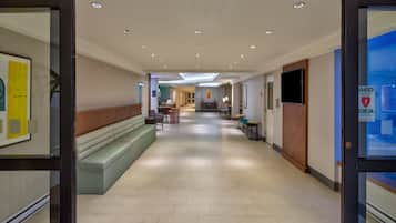 Un lobby moderno de hotel con mostrador de recepción, zona de estar y acceso despejado a los ascensores.