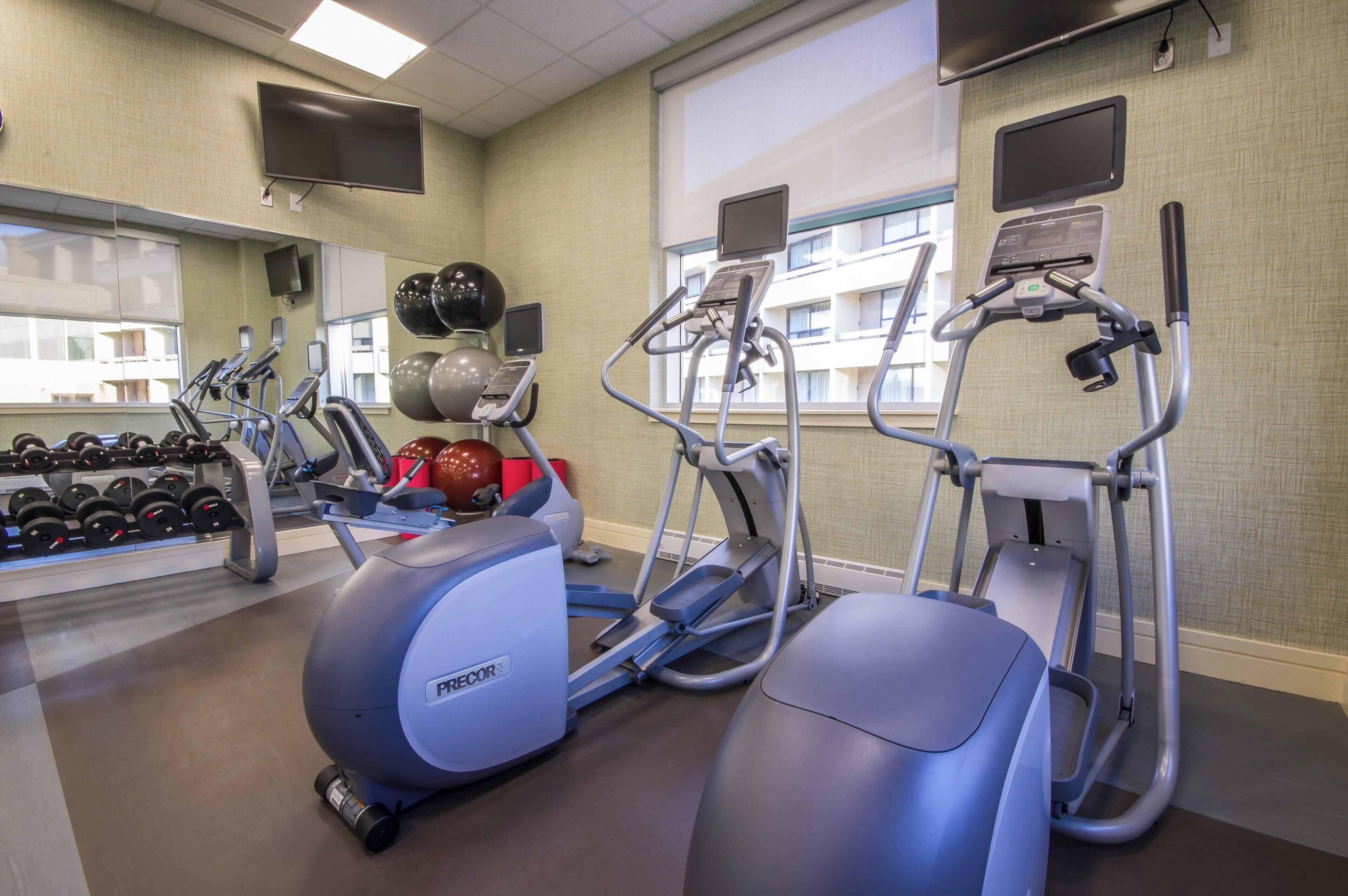 Ett gym med löpband, en crosstrainer, hantlar och träningsbollar.