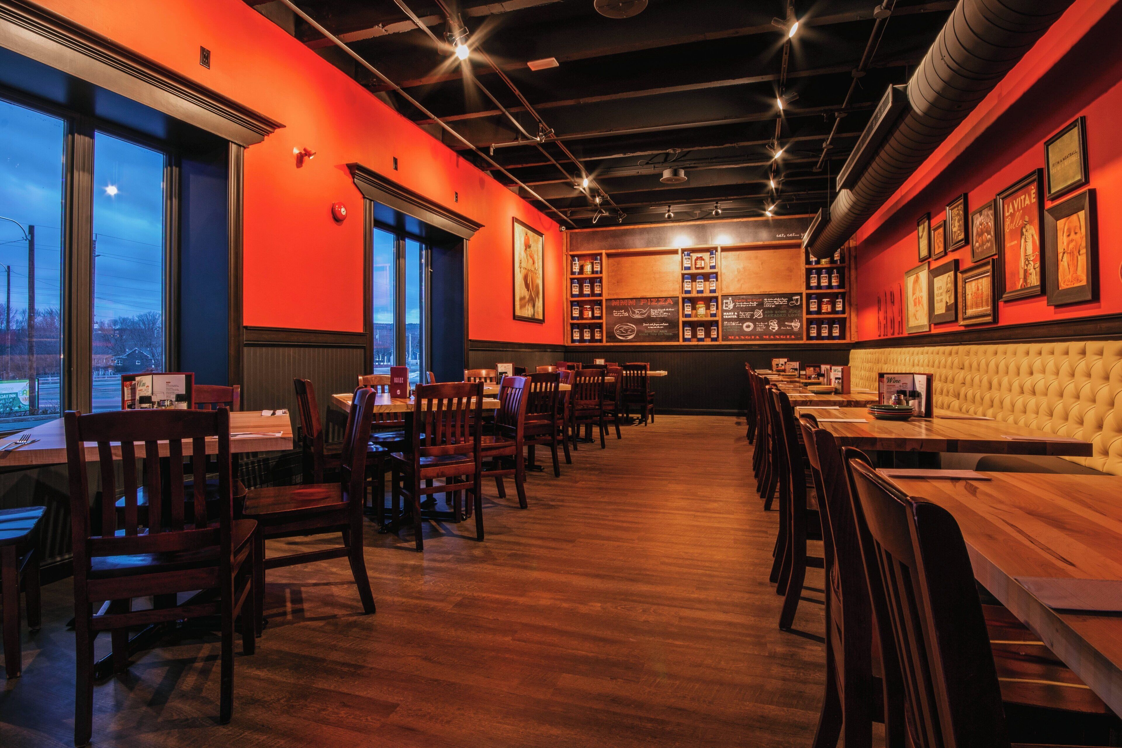 A restaurant interior with wooden tables and chairs, a bar area, and framed pictures on the walls.