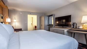 Habitación de hotel con una cama grande, un escritorio, un televisor de pantalla plana, una cafetera y una lámpara.