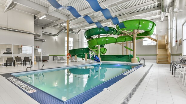 Una piscina interior amb tobogan d'aigua verd i una decoració de llaç blau.