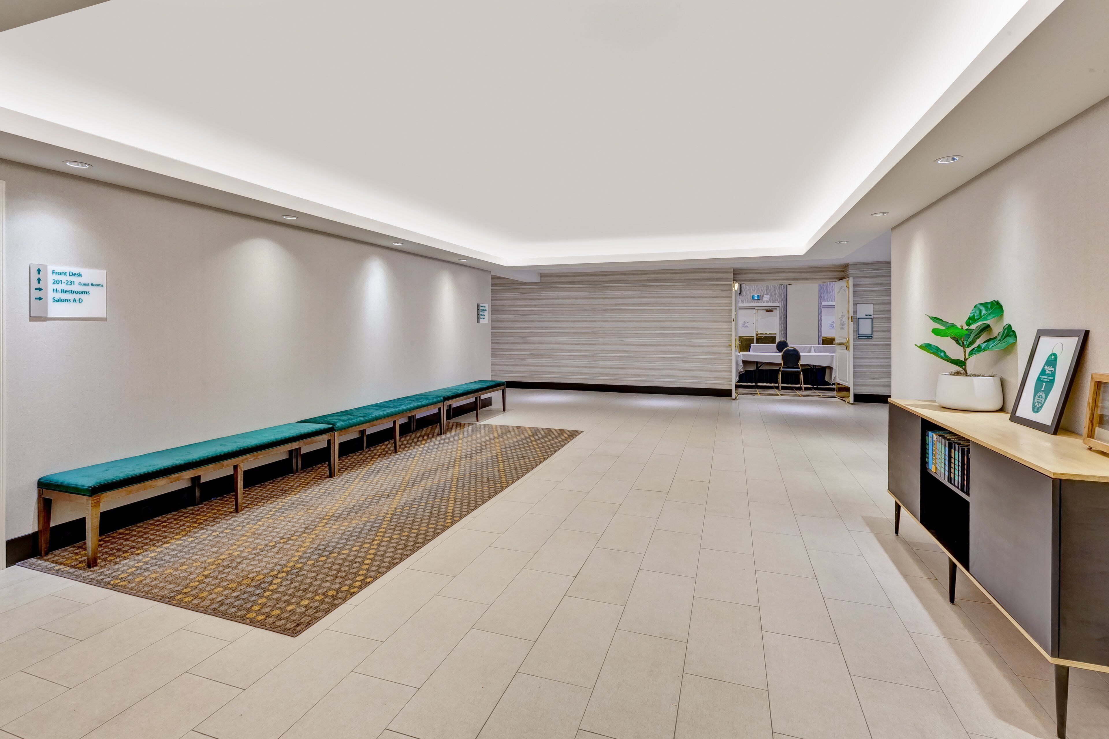 A spacious lobby with a long bench seating area, a reception desk, and a patterned rug.