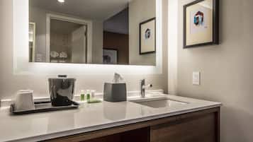 Un baño moderno con un lavamanos blanco, un espejo grande y un cuadro en la pared.