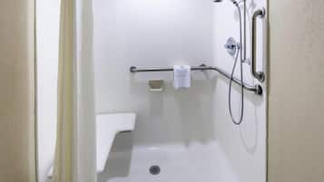 Et hvidt badeværelse med bruser, gelænder, håndklædetørre og toilet.