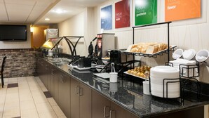 Un buffet de petit-déjeuner proposant une variété d’aliments, notamment du pain, des viennoiseries et une machine à café.
