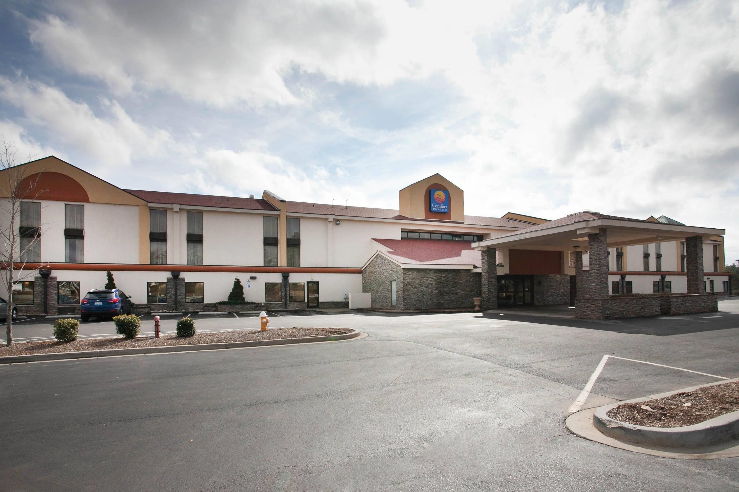 A Comfort Inn & Suites hotel with a parking lot, a covered entrance, and a clear sky.