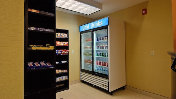 Un espace équipé d’un distributeur automatique et d’un présentoir réfrigéré portant l’inscription « boissons fraîches », où sont exposées diverses boissons.