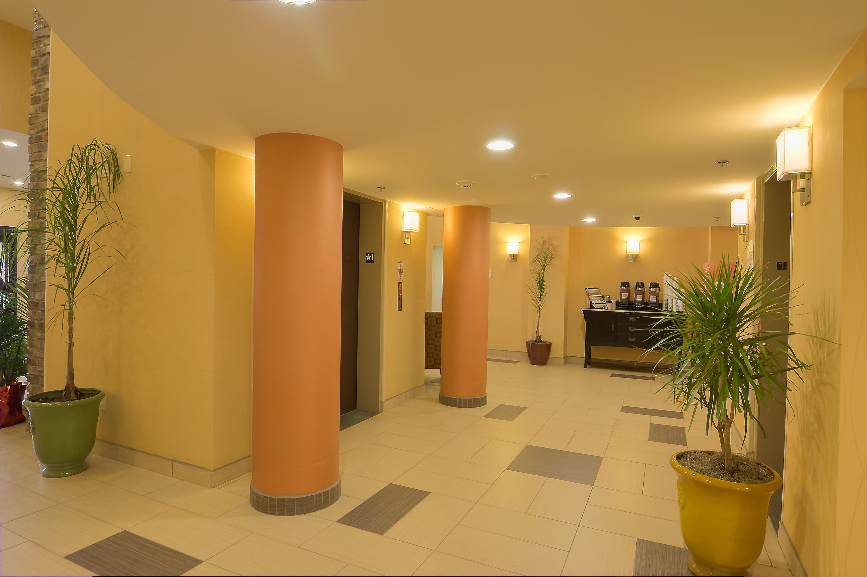 Um saguão de hotel com pilares imponentes, plantas em vasos e uma área de recepção.