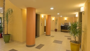 Un hall d’hôtel doté de grandes colonnes, de plantes en pot et d’un espace de réception.