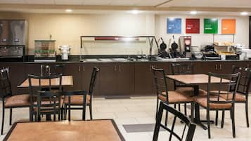 A hotel breakfast area with a self-service counter, seating, and a coffee machine.