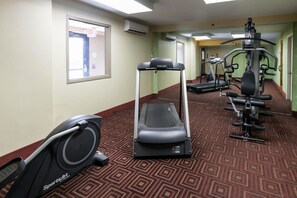 Een hotel fitnessruimte met cardioapparatuur, waaronder een loopband en een elliptische trainer, en krachttrainingsapparaten.