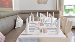 A dining area with a long table set for a meal, surrounded by cushioned seating. - Best Western Queens Hotel Pforzheim-Niefern (Niefern)