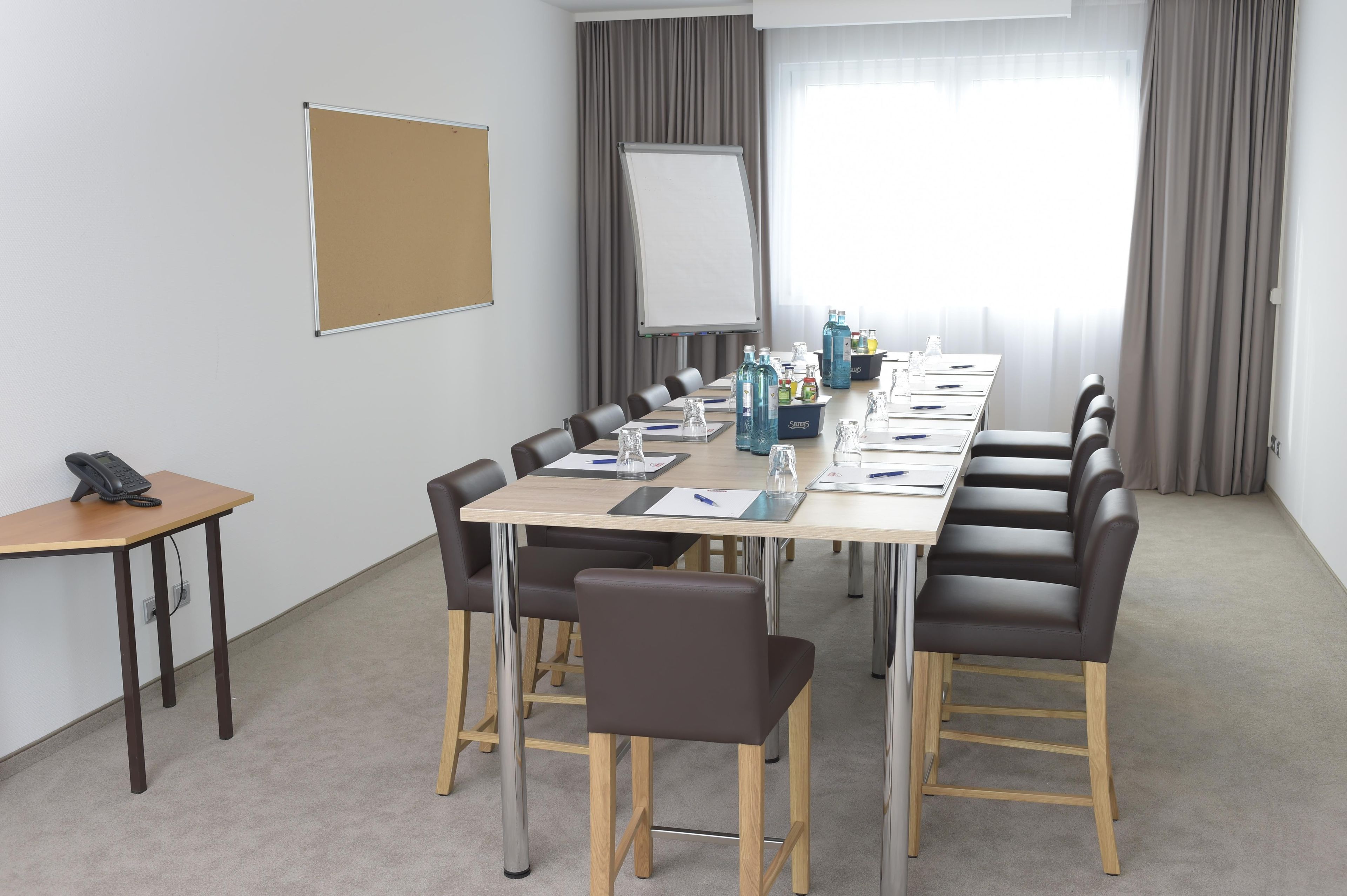 A conference room with a long table, chairs, a whiteboard, and a flip chart.