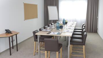 A conference room with a long table, chairs, a whiteboard, and a flip chart.