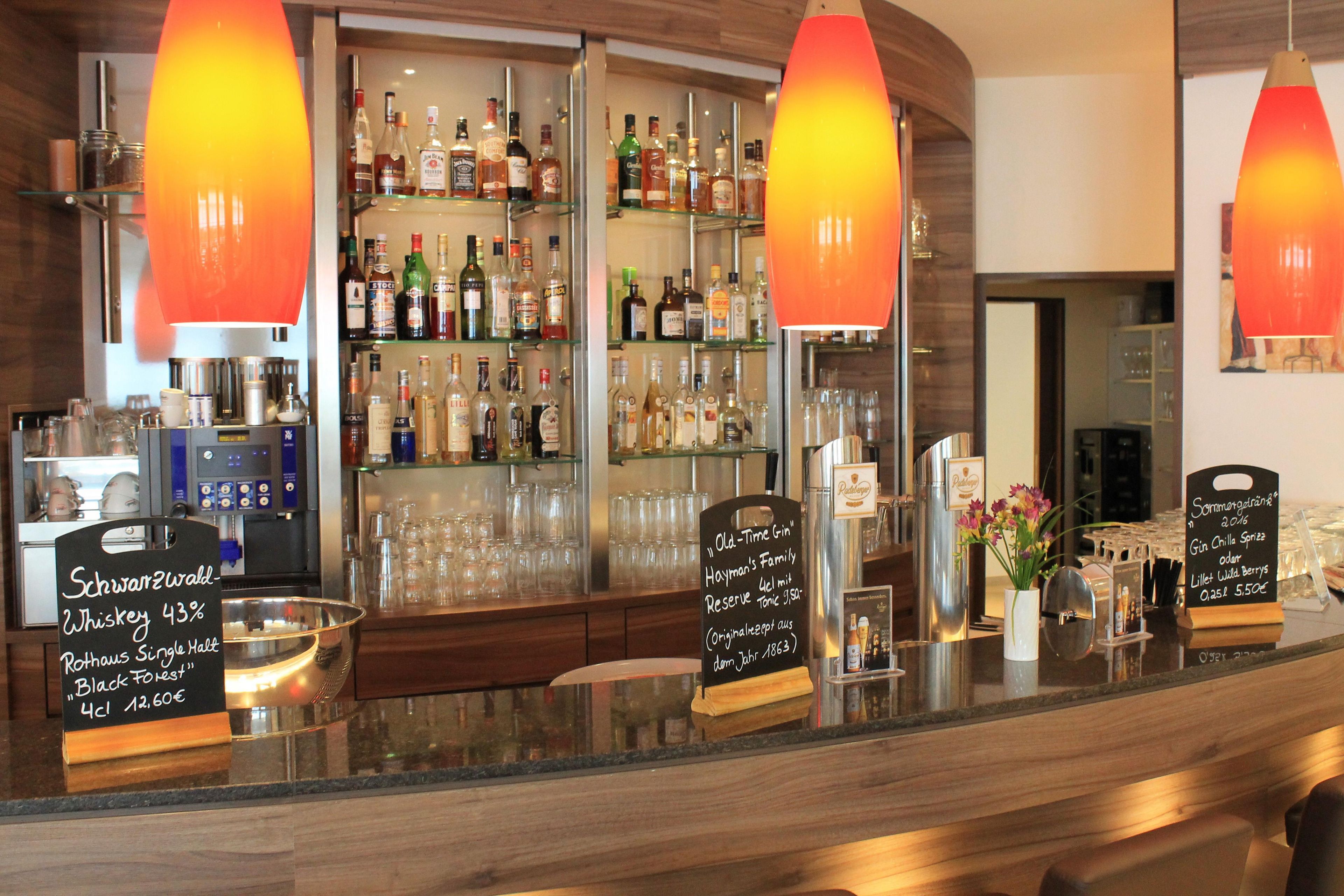 A bar area with a variety of liquor bottles, a selection of glasses, and a sign indicating a whiskey selection.