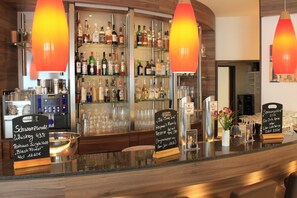 Eine Bar mit einer Auswahl an Spirituosenflaschen, verschiedenen Gläsern und einem Schild, das eine Whiskey-Auswahl anzeigt.