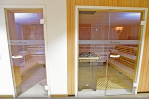 A sauna and a sanarium room with wooden benches, glass doors, and a small shelf.