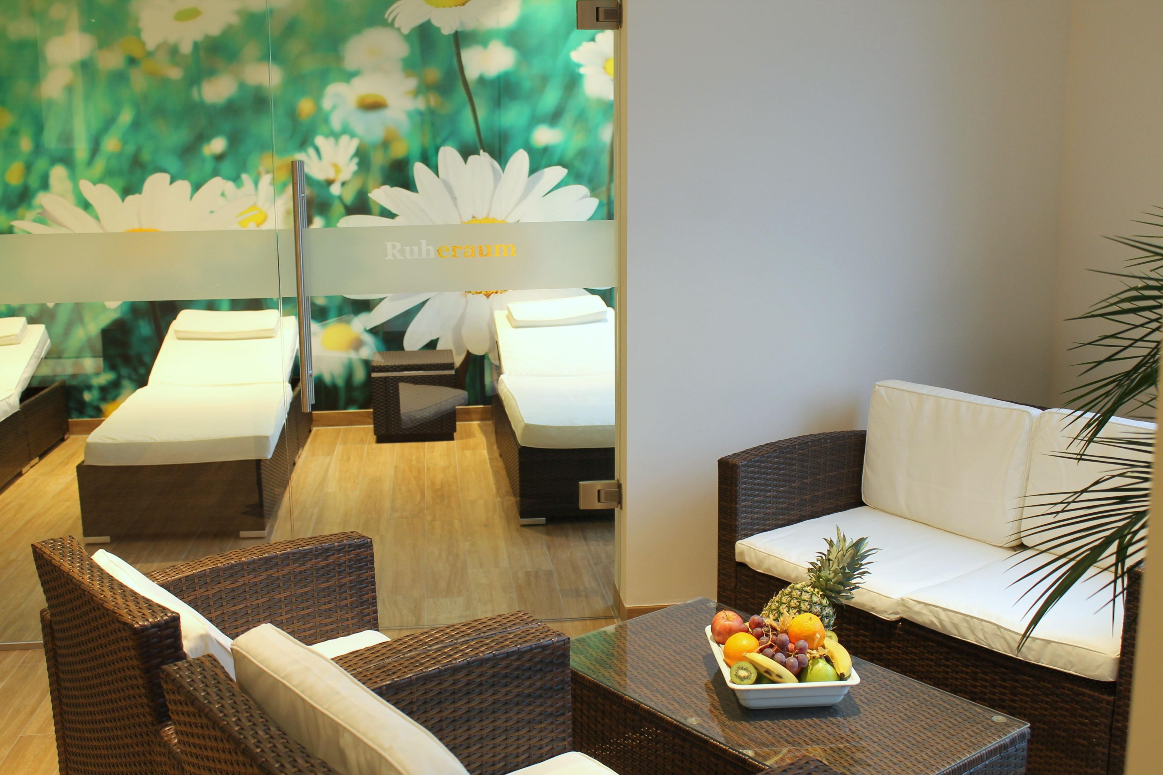 Ein Hotelzimmer mit einem Bett, einer Couch, einem Korbstuhl und einem Tisch mit Obst.