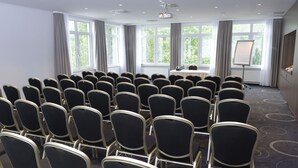 A conference room with rows of black chairs, a table with a projector, and large windows with curtains. - Best Western Queens Hotel Pforzheim-Niefern (Niefern)
