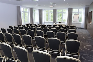 A conference room with rows of black chairs, a table with a projector, and large windows with curtains. - Best Western Queens Hotel Pforzheim-Niefern (Niefern)
