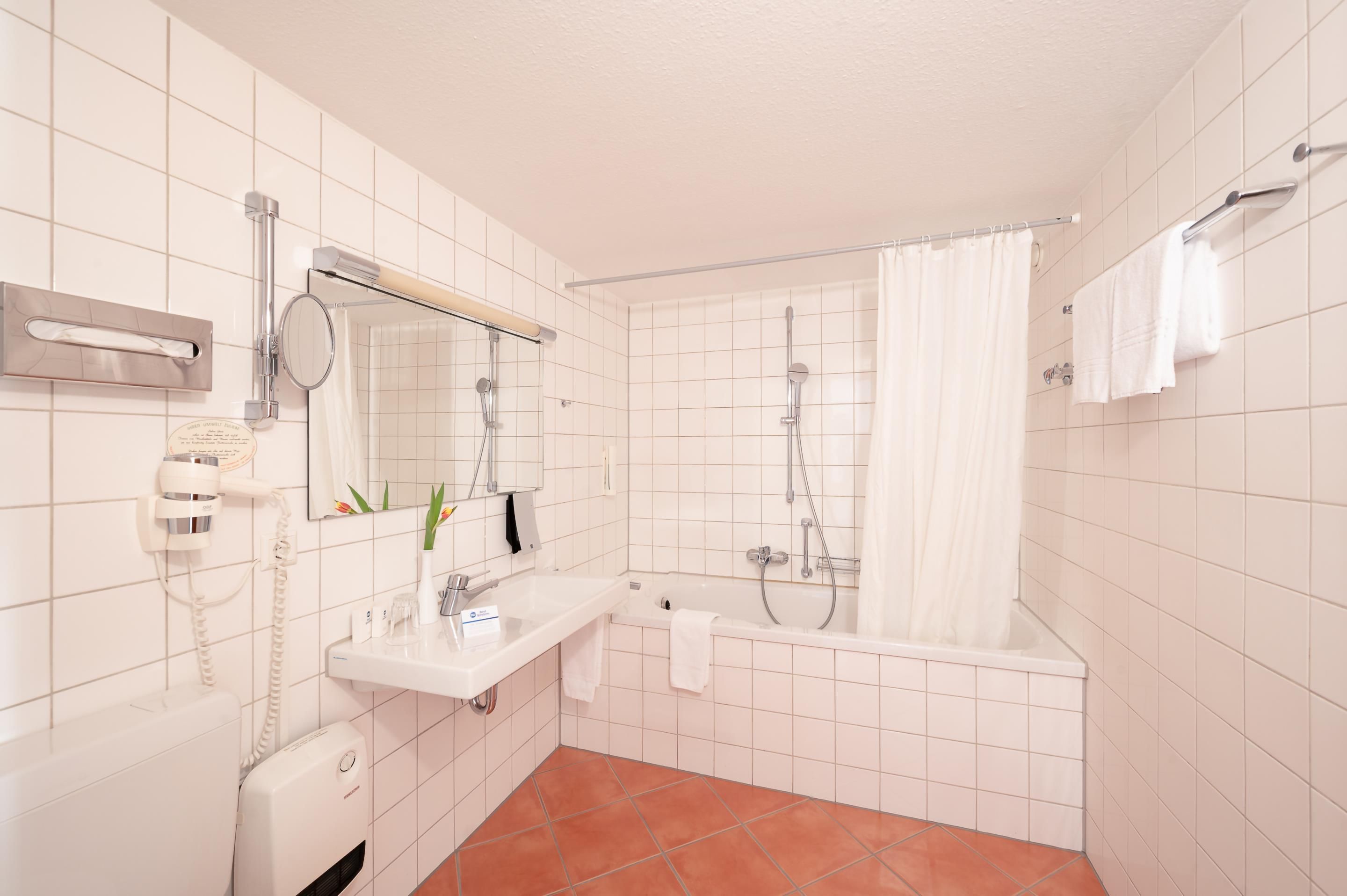 Een badkamer met een wit wastafelmeubel, spiegel en een douche met gordijn.