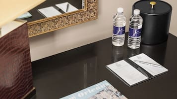 A hotel reception desk with a map of New Orleans, two water bottles, a black cylindrical container, and a pen on a brochure.