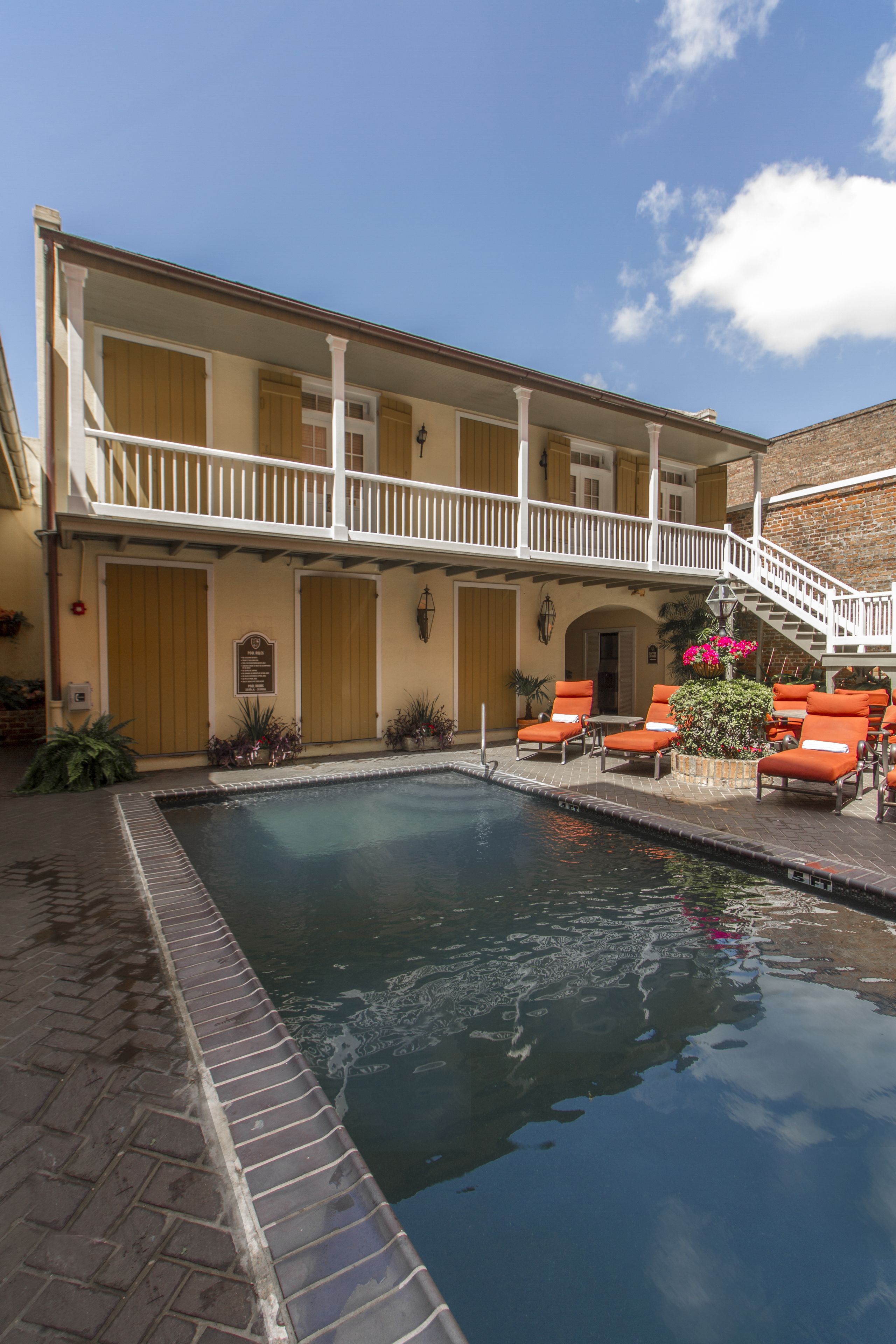 A pool area with lounge chairs and a staircase leading to an upper level.